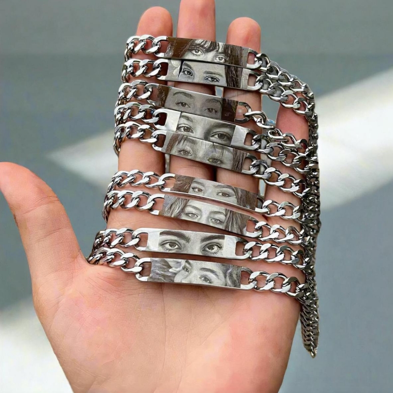 Row of Held Gaze eye-engraved ID-plate bracelets held in a hand